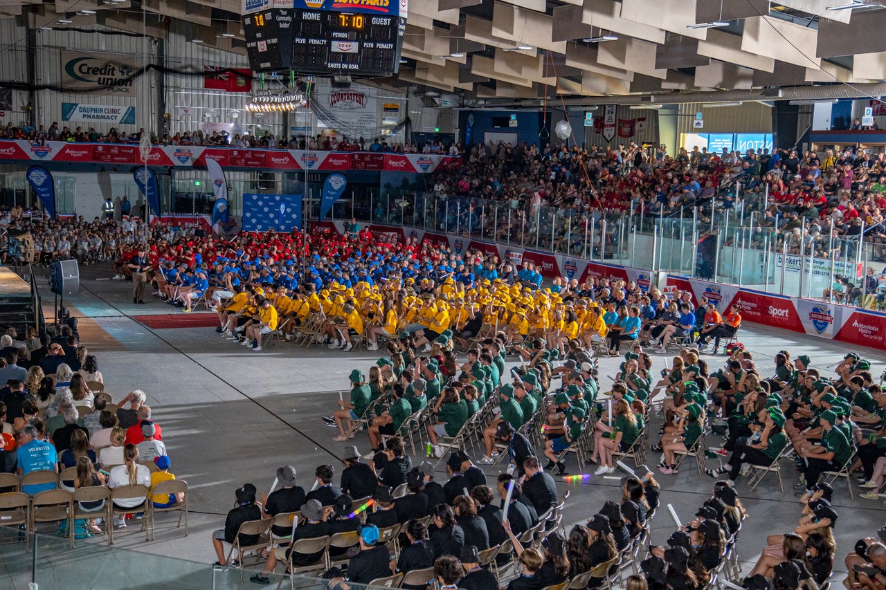 Hundreds of young athletes sit in an arena for the Manitoba Games along with Manitoba Hydro mascots.