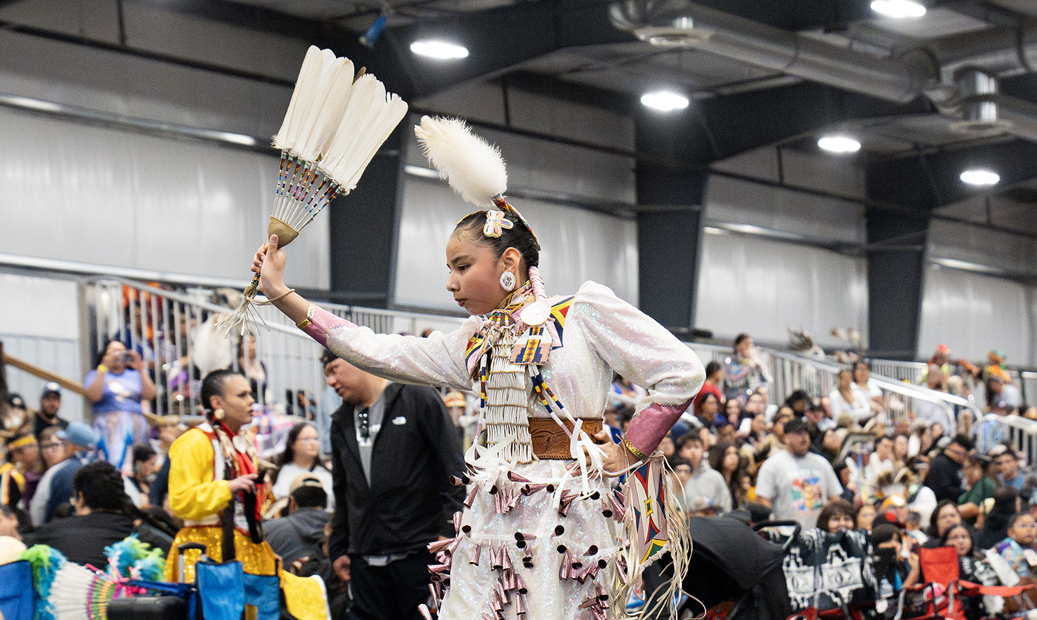 An Indigenous dancer in traditional clothing dances in front of an audience at the Manito Ahbee Festival.