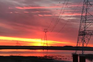 Sunset overlooking a river with hydro lines running across.