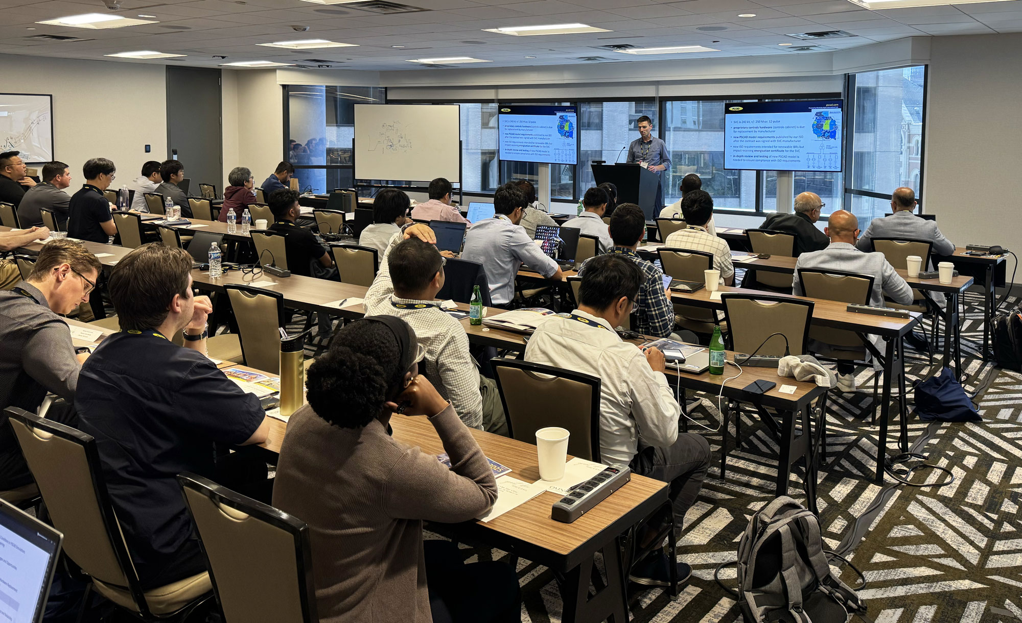A classroom of engineers siting in rows listening to a presenter.