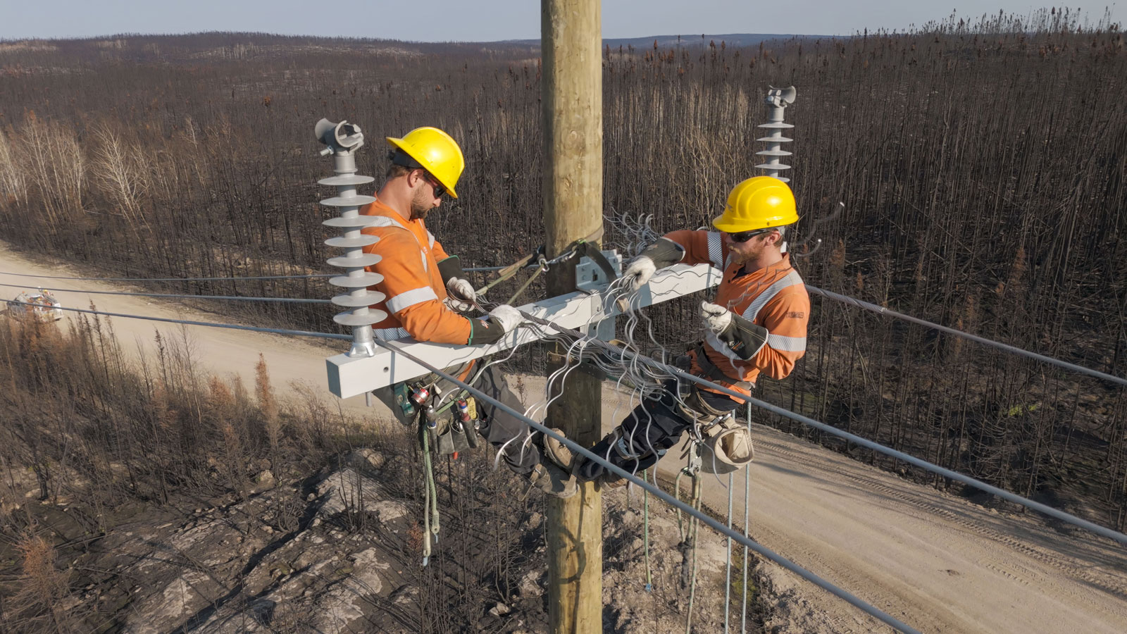 Two Hydro workers on a new hydro pole making repairs to equipment.